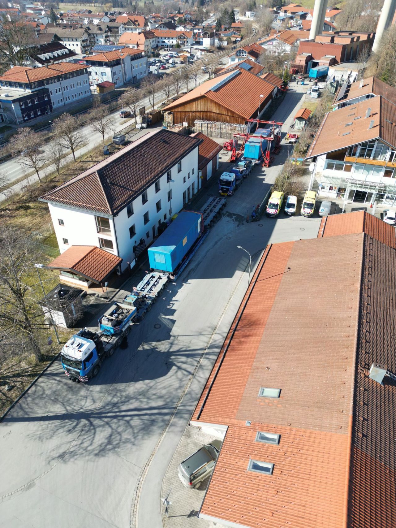 Aerial view of heavy haulage trucks transporting large generator units through the streets of Hausham.